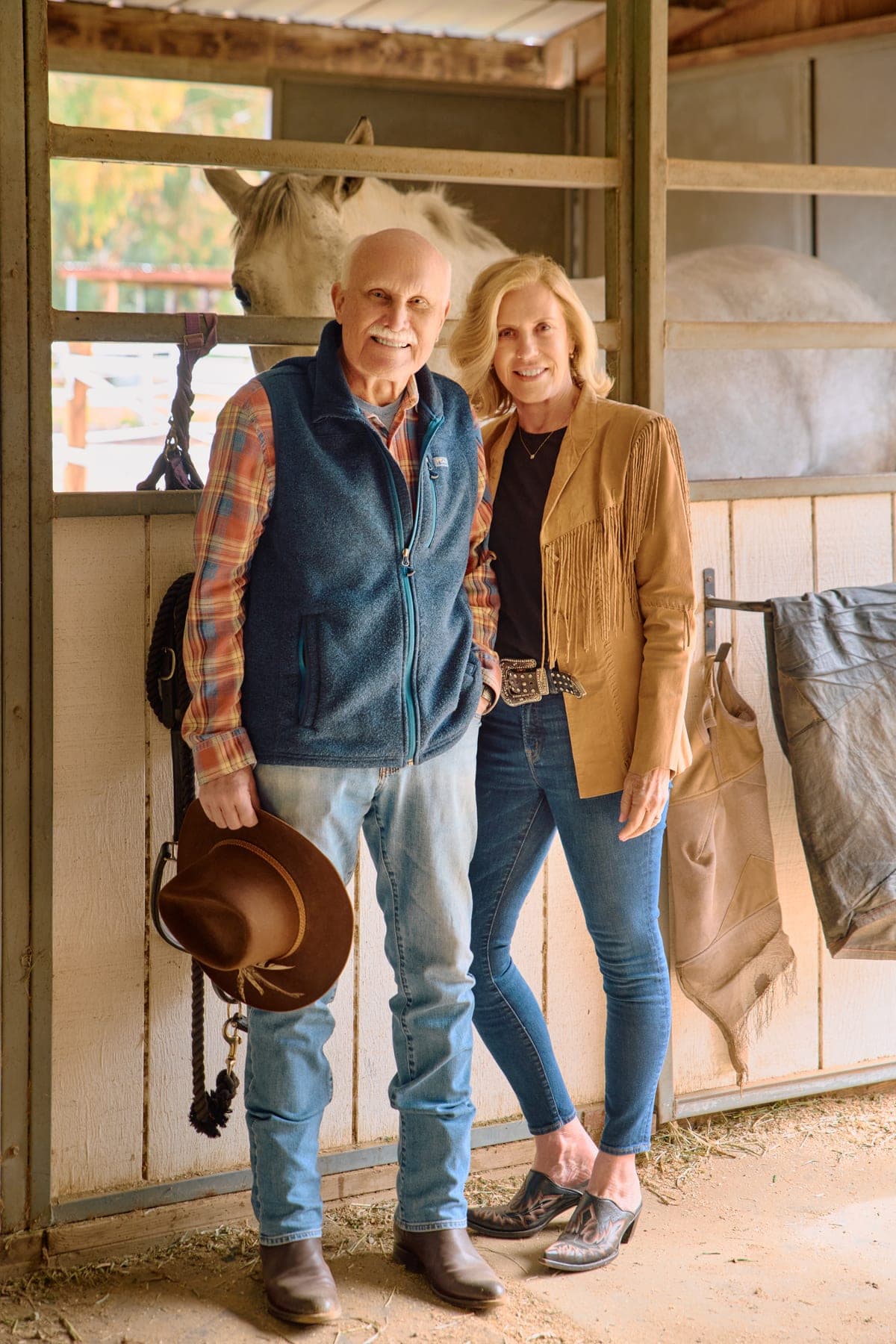 Ann Marie Nugent and Jim Walberg in a barn, with a horse in the stall behind them.