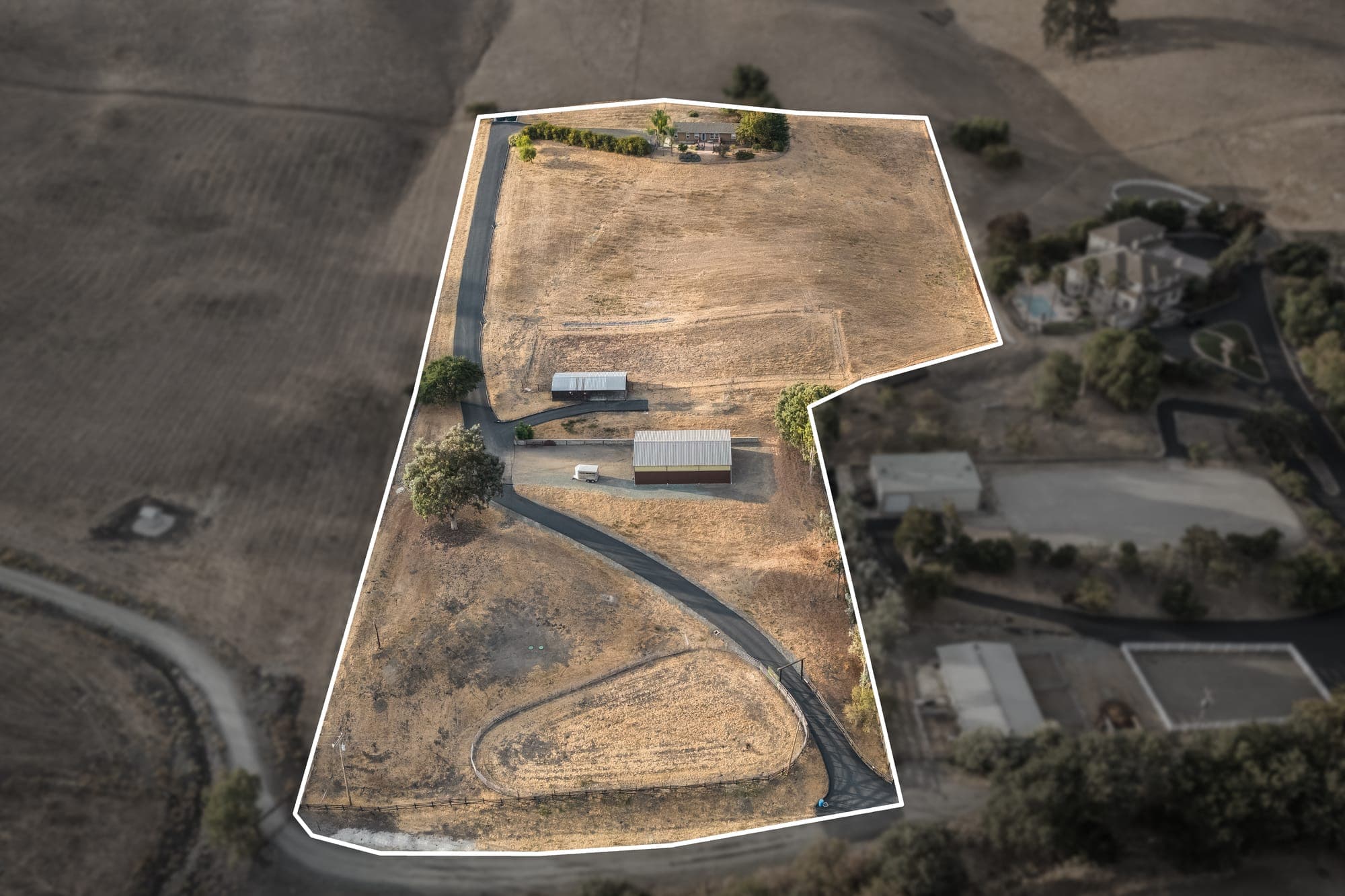 Overhead aerial of the property with an outline drawn around the parcel, showing the drive, residence, shop, barn, and open land.