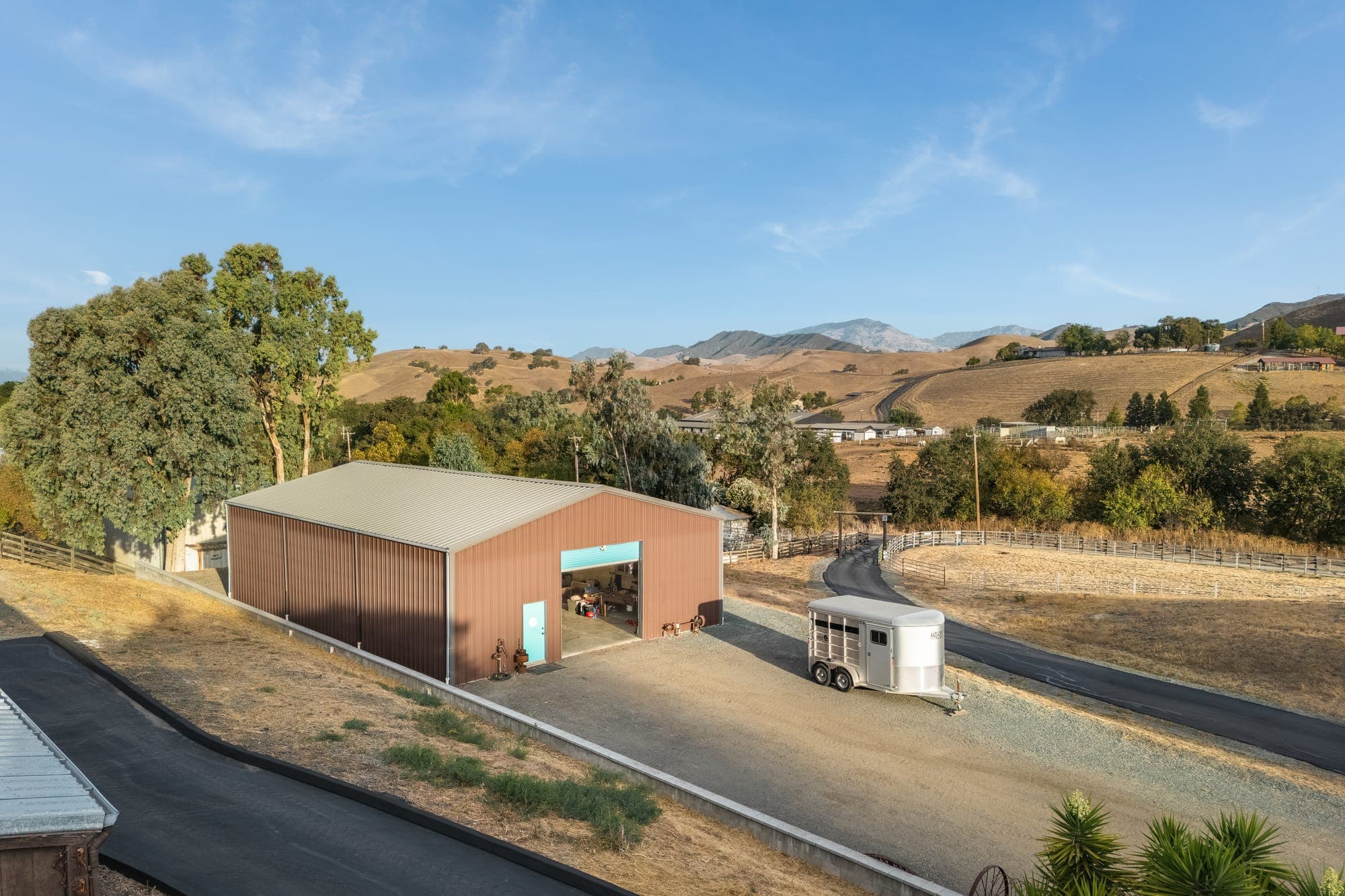 The shop set into the hillside above the drive, with the valley and distant ridges behind.
