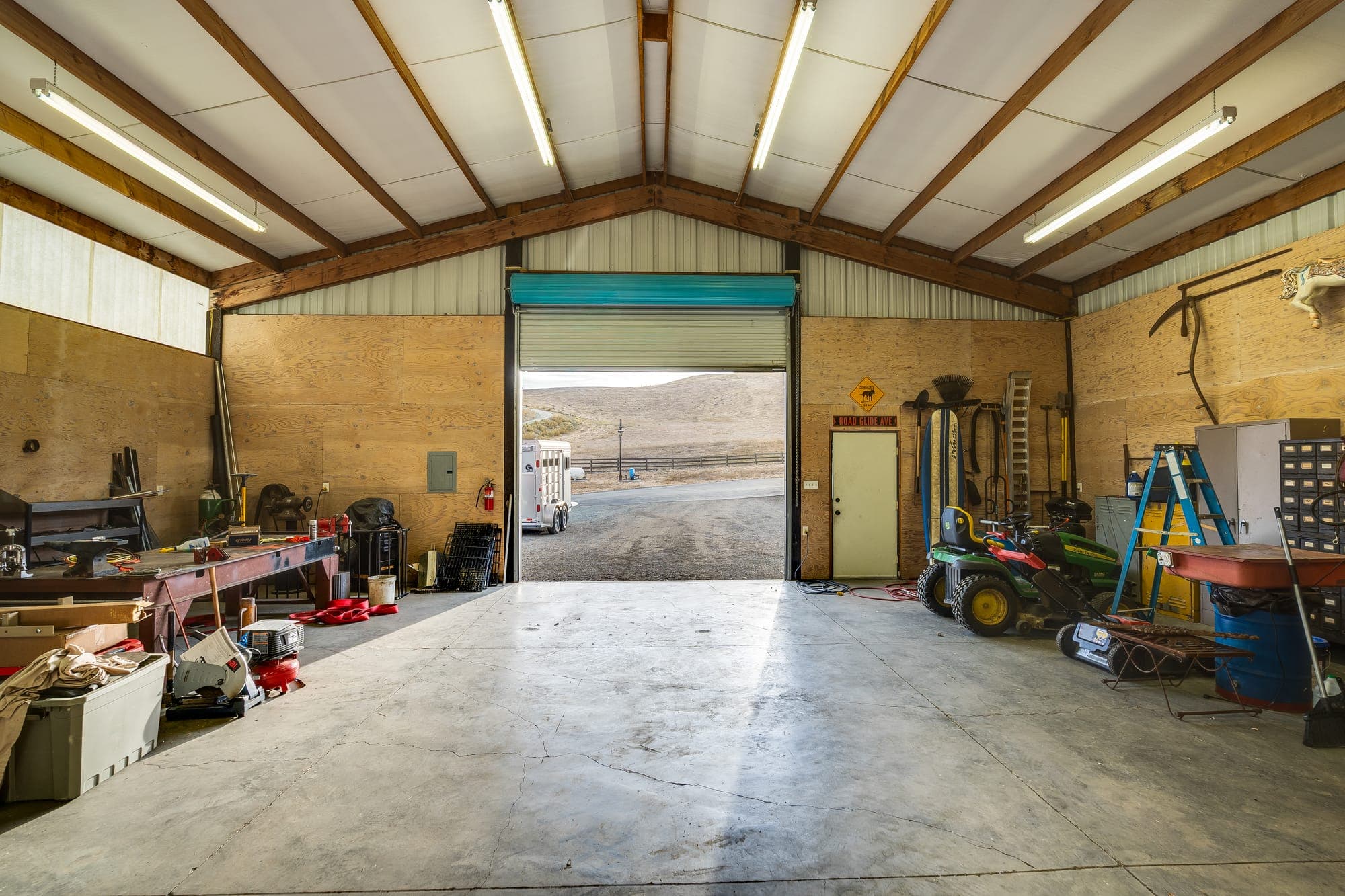 Inside the shop looking out through the open roll-up door toward the hills.