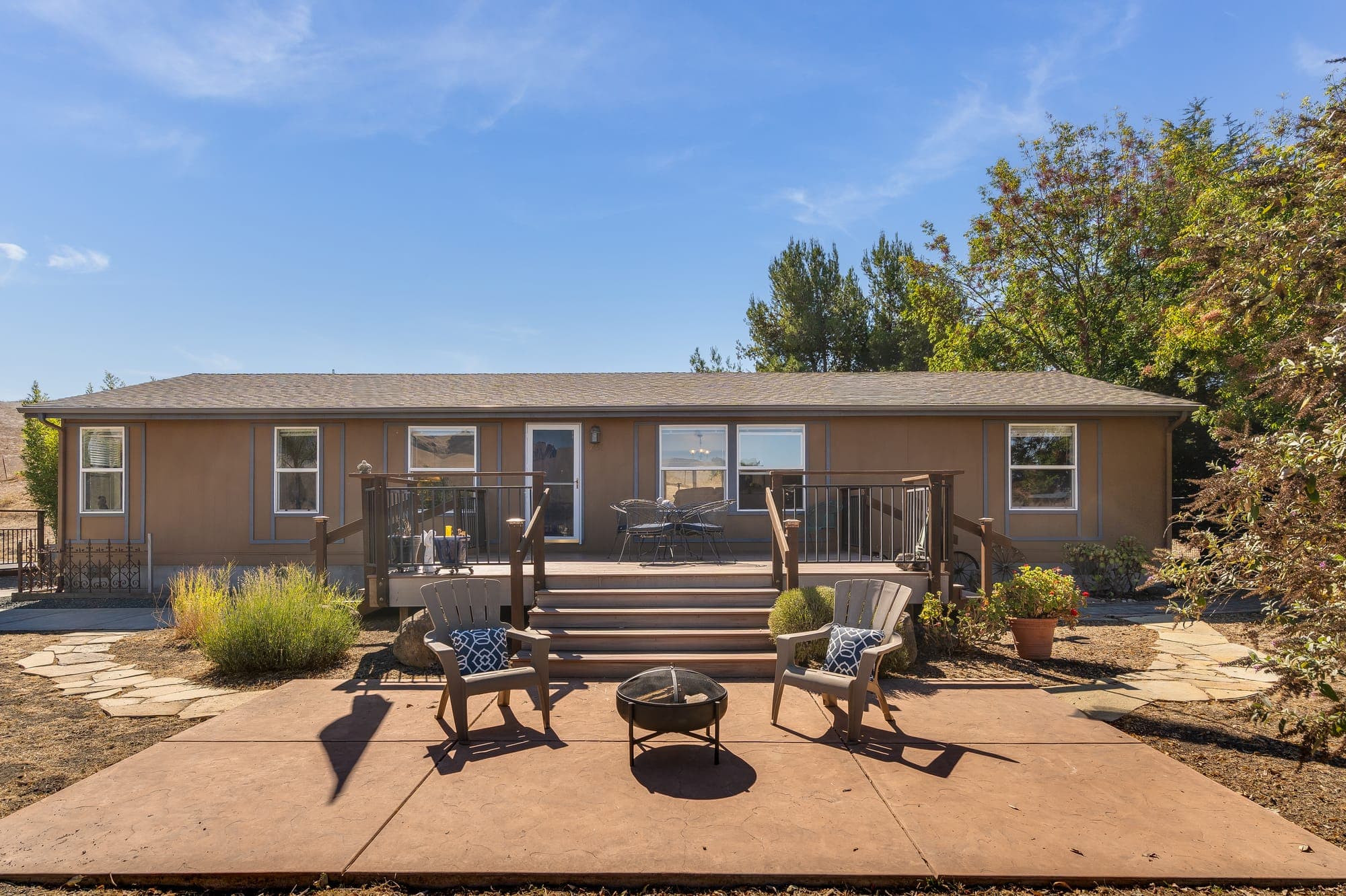 The front patio with chairs around a fire bowl, steps rising to the deck.