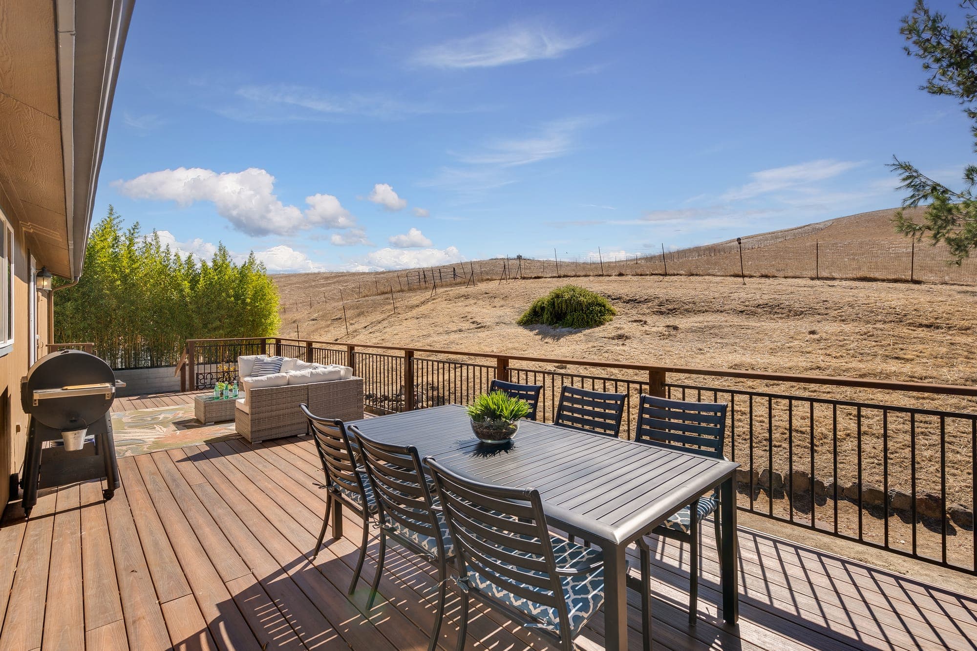 Outdoor dining table on the deck looking toward open hillside.