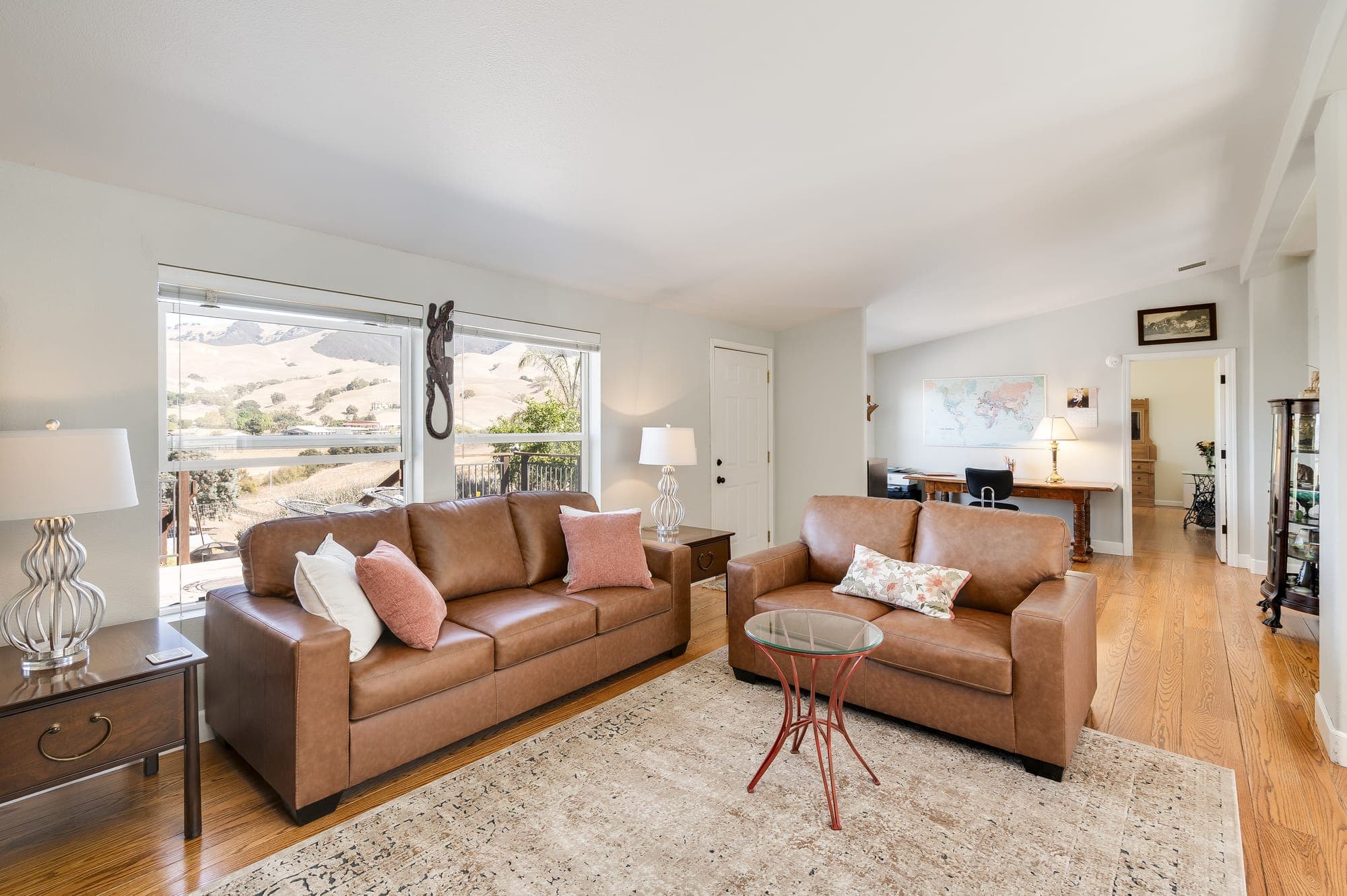 The living room with leather sofas and large windows framing the hills.
