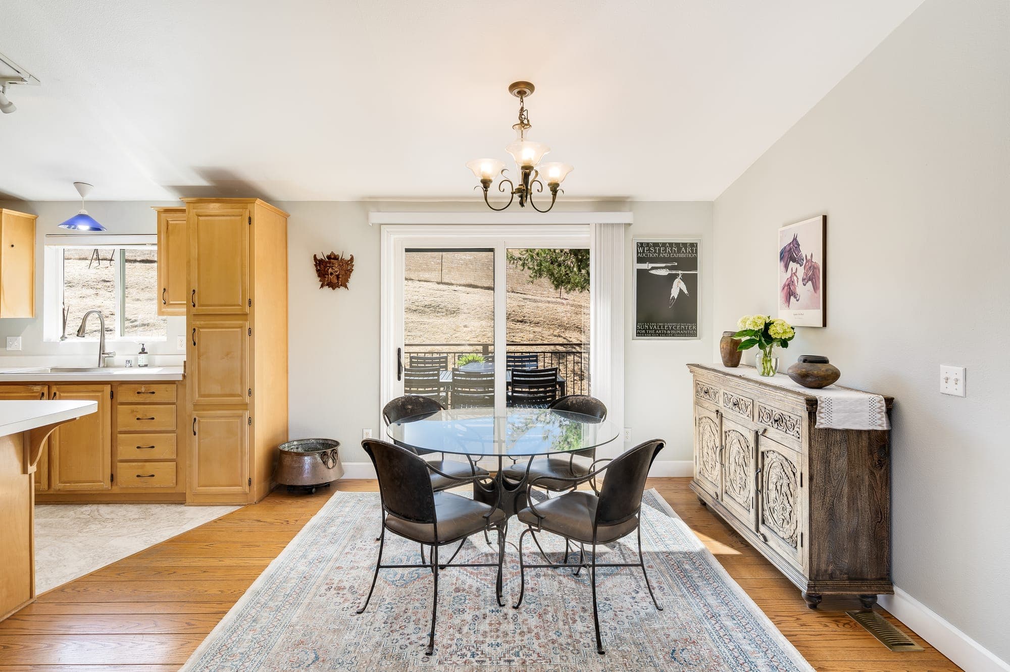 The dining area with a round table, a slider to the deck, and the kitchen beside it.