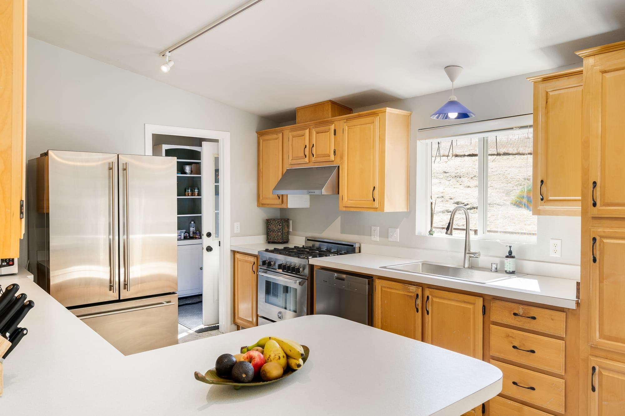 The kitchen with stainless appliances, a gas range, and a window over the sink.