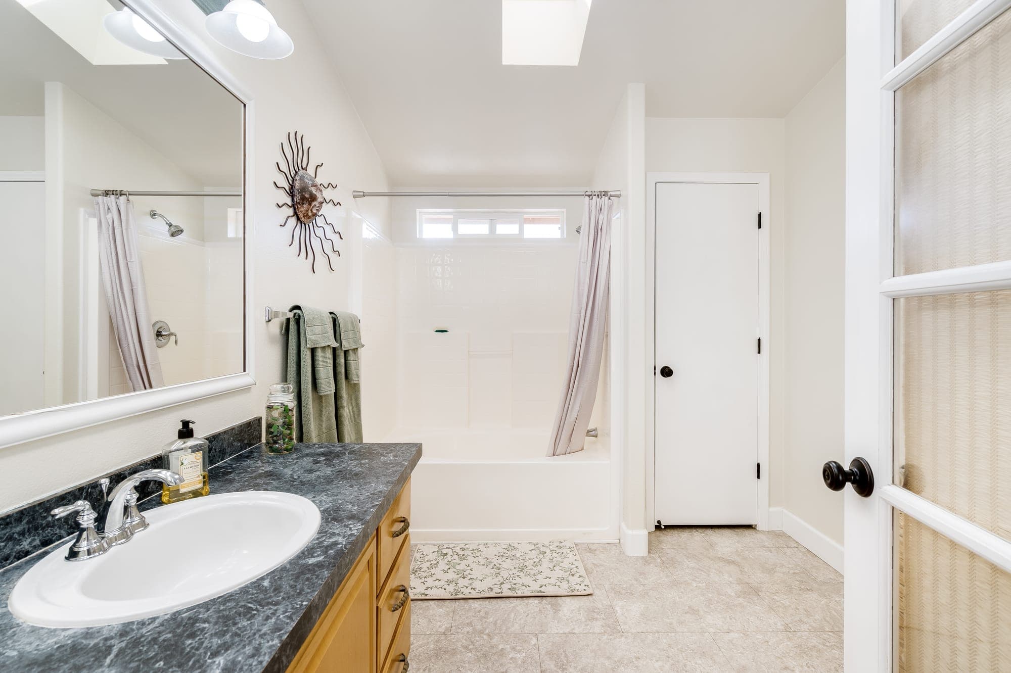 A bathroom with a vanity, a tub and shower, and a skylight.