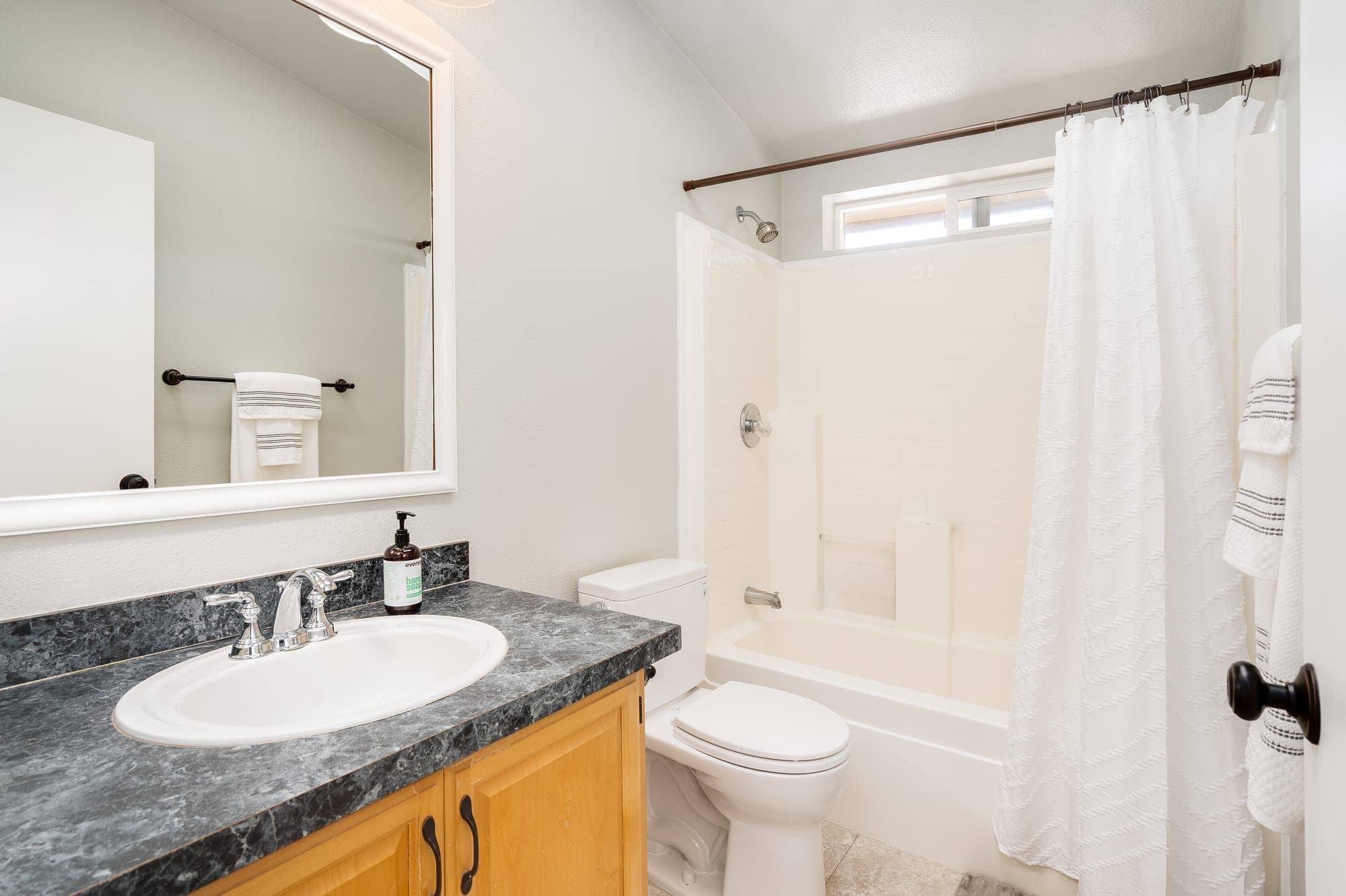 A bathroom with a vanity and a tub and shower.